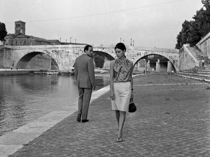 Un hombre y una mujer se dedican miradas tímidas junto a un río en Italia en los años sesenta, aproximadamente.