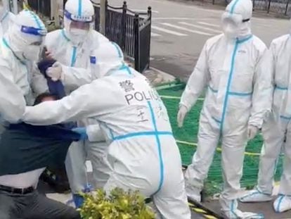 Varios policías inmovilizan a un hombre que protesta contra la conversión de unos apartamentos en centros de cuarentenas en Pudong (Shanghái).