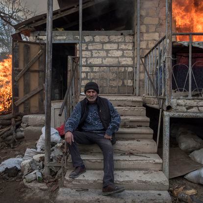 In this image released by World Press Photo, Thursday April 15, 2021, by Valery Melnikov, Sputnik, part of a series titled Paradise Lost, which won the first prize in the General News Stories category, shows Areg sits outside a burning house in the village of Karegakh, Nagorno-Karabakh, on 25 November. Some village residents burned their houses before leaving areas that were to return to Azerbaijani control following the November peace agreement. (Valery Melnikov, Sputnik, World Press Photo via AP)