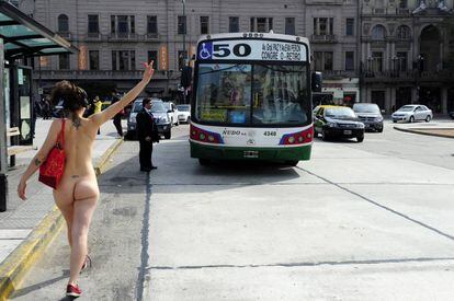 Una de las integrantes de UrbaNudismo simula parar un bus.
