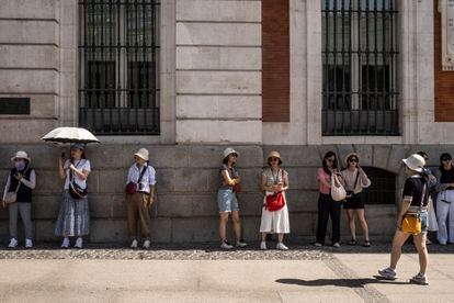 Varios turistas pretenden protegerse del calor en la nueva Puerta del Sol de Madrid. 