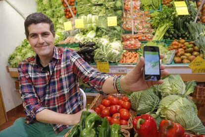 Íñigo Busto muestra la aplicación LurakiApp para móvil en una frutería