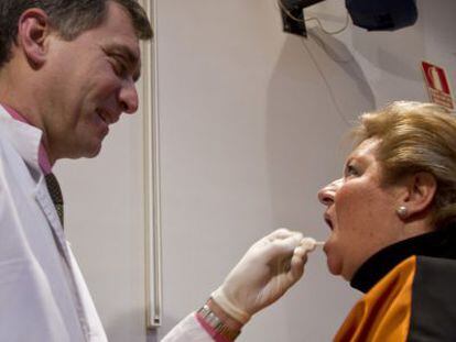 Un sanitario extrae células epiteliales de la boca de una mujer para obtener su ADN.