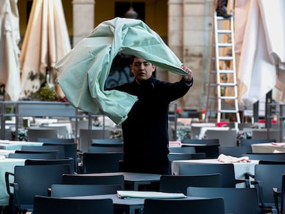 Un trabajador de la hostelería prepara una mesa en una terraza.