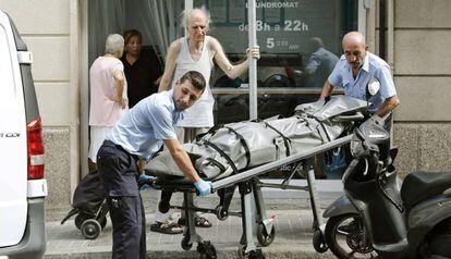 Operarios retiran el cuerpo sin vida de la víctima en el distrito Sants-Montjuïc de Barcelona.