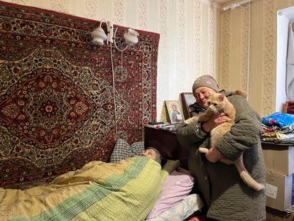 Liudmila, enfermera jubilada de 79 años, postrada en la cama del apartamento en el que vive con Natacha, de pie con su gato en brazos, en Limán.