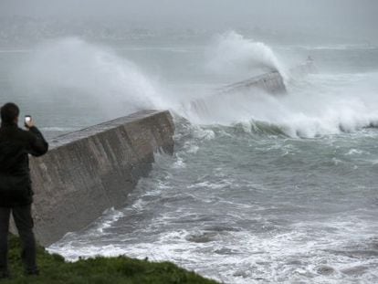 Un hombre fotograf&iacute;a las grandes olas que rompen en un muelle en Esquibien, en la zona oeste de Breta&ntilde;a, Francia.