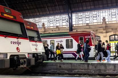 Varias personas pasaban el lunes junto a trenes de cercanías en la Estación del Norte de Valencia.