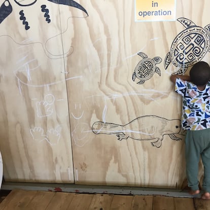 Aisan, de 3 años, pinta con una tiza en un tablerillo decorado con animales en la cubierta de mujeres.