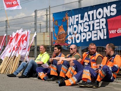 Cinco trabajadores sentados ante una pancarta que reza "Alto al monstruo de la inflación", durante una huelga a comienzos de junio en el puerto de Hamburgo.