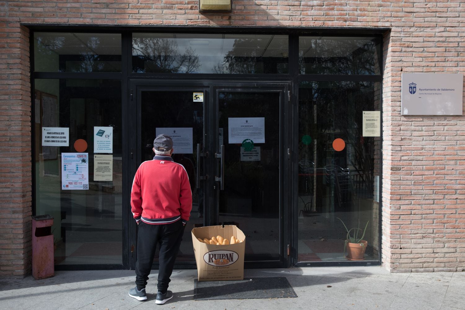 Un jubilado lee la nota informativa que cuenta los motivos por los que se encuentra cerrado el centro municipal de mayores de Valdemoro (Madrid).