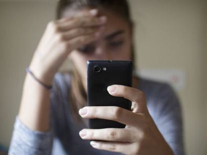 Una adolescent trista després de rebre una amenaça a través del mòbil.