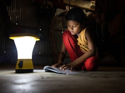 Una niña lee en su casa utilizando una luz de energía solar en Jaliyapalong, Cox's Bazar, Bangladés.