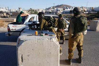 Soldados israelíes registran un coche en un control entre Hebrón y la aldea de Yatta.