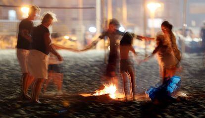 Un grupo de personas baila alrededor de una hoguera en la playa de San Juan de Alicante, donde numerosas personas disfrutaron de la noche mágica de San Juan. 