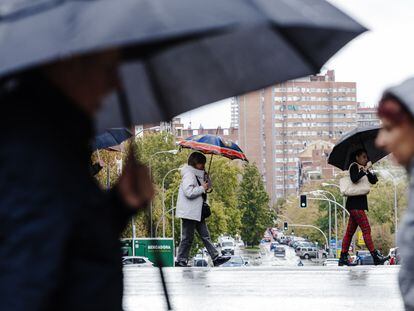 Varias personas se protegen de la lluvia en Madrid.