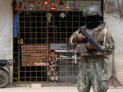 Un niño mira a través de los barrotes a un militar apostado en la calle, en Guayaquil (Ecuador).