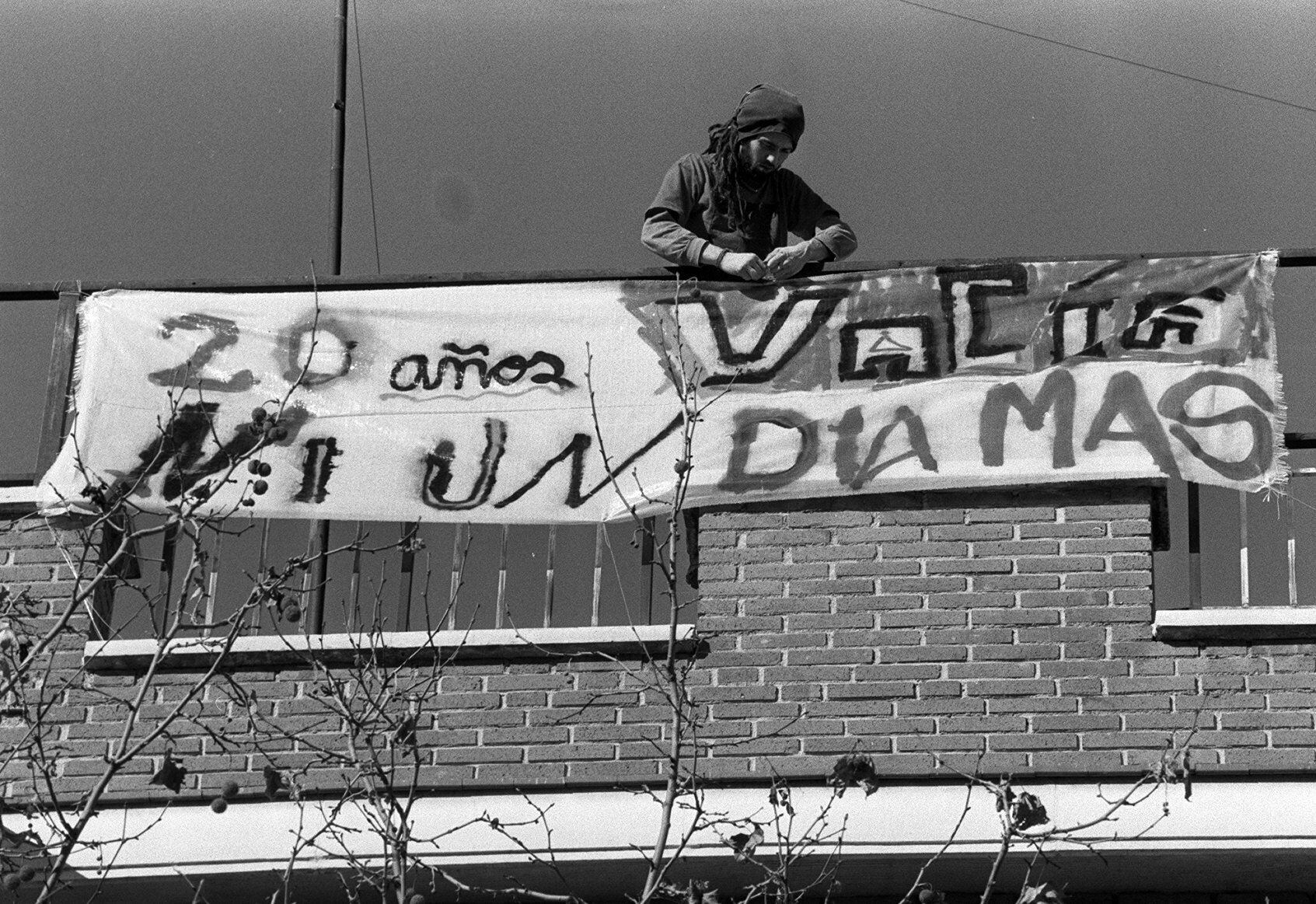 Un joven coloca una pancarta en un edificio okupado de Lavapiés en enero de 1999.