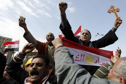 Los manifestantes llevan a hombros a un musulmán con un Corán (izquierda) y a un copto con una cruz.