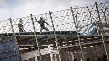 Varias personas tratan de cruzar la valla de Melilla en junio.