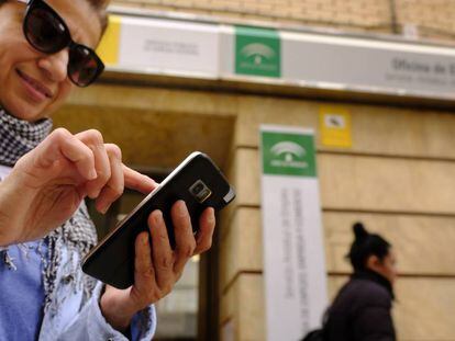 Una desempleada consulta su móvil tras pasar por una oficina de empleo en Sevilla esta semana.