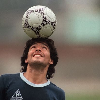 (FILES) In this file photo taken on May 22, 1986 Argentine football star Diego Maradona, wearing a diamond earring, balances a soccer ball on his head as he walks off the practice field following the national selection's practice session in Mexico City. - Argentinian football legend Diego Maradona passed away on November 25, 2020. (Photo by JORGE DURAN / AFP)