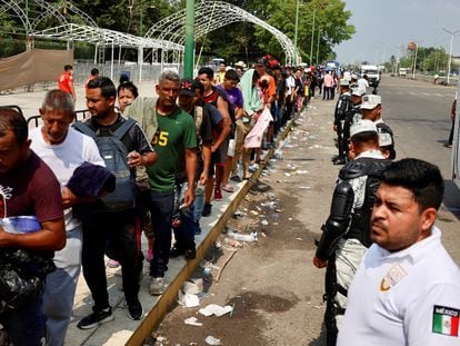 Integrantes de la Guardia Nacional hacen fila mientras migrantes esperan para abordar un camión a Tuxtla Gutiérrez (Estado de Chiapas), el 12 de mayo de 2023.