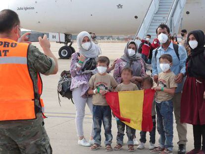 Un grupo de afganos ante un avión procedente de Dubái con evacuados desde Afganistán a su llegada este miércoles a la Base Aérea de Torrejón de Ardoz (Madrid), el 27 de agosto.