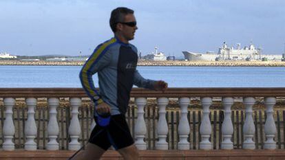 Un hombre corre por el paseo marítimo, con la base militar al fondo.