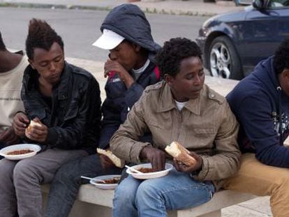 Un grupo de voluntarios ofrece comida a inmigrantes eritreos del centro de internamiento de Lampedusa, Italia.