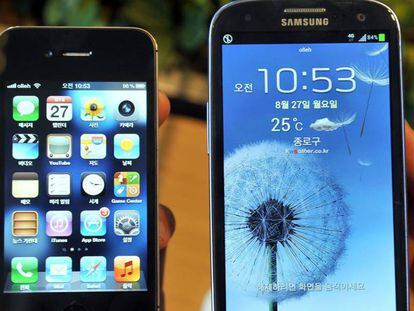 Fotografía de agosto de 2012 de un empleado con el iPhone 4s de Apple (izquierda) y el Samsung Galaxy S3 (derecha) en una tienda de móviles en Seúl