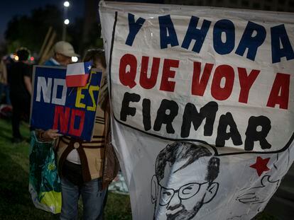 Una mujer sostiene una manta con la imagen de Boric y la frase "¿Y ahora qué voy a firmar?", durante una manifestación frente a La Moneda, este domingo.
