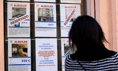 Una mujer mira anuncios de viviendas en una inmobiliaria
