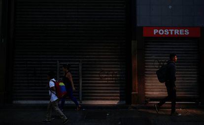 Tres personas pasan por delante de un restaurante cerrado por el apagón.