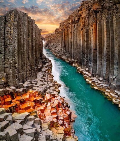 Hasta su aparición en la revista de a bordo de Wow Air, en 2017, pocos turistas sabían de la existencia del cañón Studlagil, al este de <a href="https://elviajero.elpais.com/tag/islandia/a" target="_blank">Islandia</a>, y sus imponentes columnas de basalto, de 30 metros de altura. Durante milenios permanecieron ocultas bajo el agua. La construcción, en el año 2006, de la central hidroeléctrica de Kárahnjúkar las puso al descubierto al desviar parte del curso del río glacial Jökla, que baja desde las tierras altas hasta el valle de Jökuldalur, reduciendo su caudal y la altura de su cauce. El antaño poderoso torrente que excavó el cañón fluye ahora plácido y azul entre murallas de roca magmática. Gracias a su complicado acceso, por un camino empinado y resbaladizo, se mantiene como una de las maravillas ocultas del país nórdico.