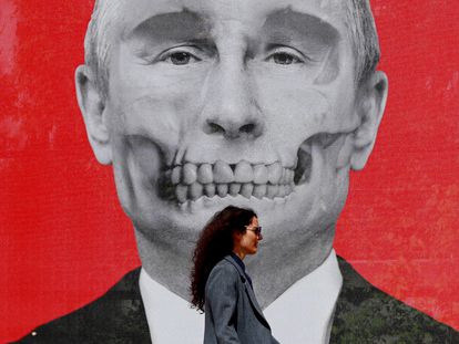 Una mujer pasa delante de un retrato del presidente ruso, Vladímir Putin, caracterizado como una calavera, durante una exposición en contra de la ofensiva militar rusa en Ucrania, en la plaza del Rey de Bucarest (Rumania) el 29 de abril.