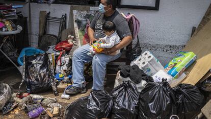 Un hombre cuida de un bebé al exterior de su casa que quedó dañada por las fuertes lluvias de la tarde el lunes en Atizapán, Estado de México