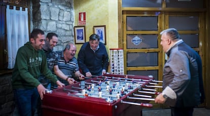 Cuatro clientes del Casal d'Alfés, del lado culé del futbolín, juegan contra Gregorio Pifarre, que defiende los colores madridistas.