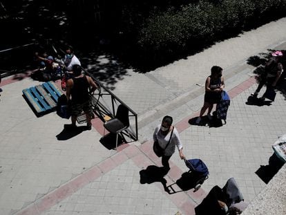 Colas de personas esperan a las puertas de la Parroquia Santa María Micaela (Madrid) para recibir una ayuda alimentaria.