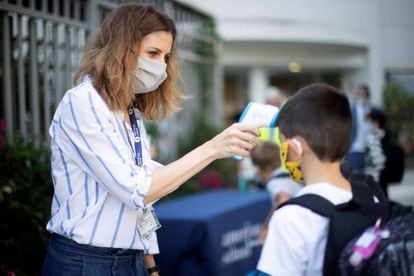 Una trabajadora toma la temperatura a un niño a la entrada del colegio privado internacional American School of Barcelona.