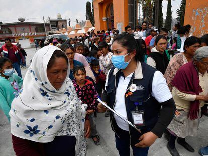 Habitantes de Santiago Xalitzintla hacen fila para recibir un kit de protección de ceniza.