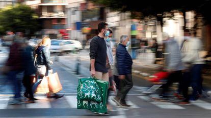 Varias personas cargan con sus bolsas en una calle de Valencia tras realizar sus compras navideñas el pasado mes de diciembre.