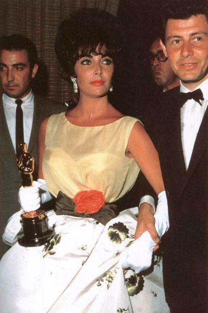 La firma Christian Dior (entonces en manos de Marc Bohan) es responsable del diseño con el que Elizabeth Taylor recogió el Oscar por su actuación en 'Una mujer marcada' en 1961. A su lado, Eddie Fisher.