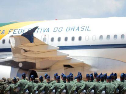 Un grupo de militares frente a un avión de la Fuerza Aérea Brasileña (FAB), en una imagen de archivo. / Vídeo: Traslado del militar de la comitiva en un furgón policial.