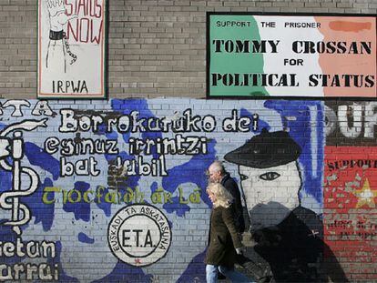 Una pareja pasa ante un mural de apoyo a ETA en Falls Road, en el barrio católico de Belfast.