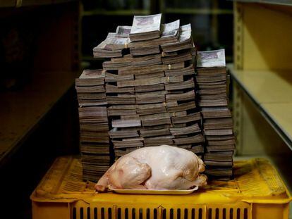 Un pollo de 2,4 kilos frente a una montaña de billetes que suman su precio —un equivalente de 1,95 euros—, en un mercado de Caracas, el 16 de agosto de 2018.