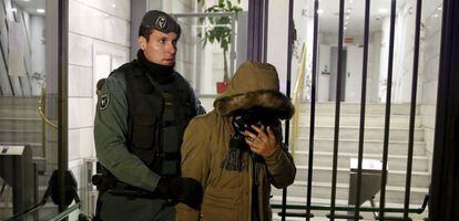 Un guardia civil conduce a un sospechoso fuera de las instalaciones del banco chino ICBC en Madrid.