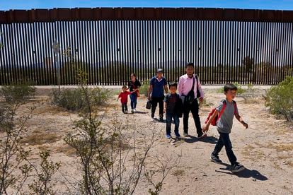 Una familia de migrantes guatemaltecos camina junto al muro fronterizo entre México y Estados Unidos, cerca de la población de Lukeville (EE UU), en agosto de 2023.