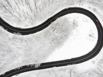 Un coche conduciendo por una carretera que atraviesa un bosque nevado en Budapest (Hungría).