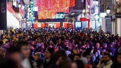 Cientos de personas pasean este martes por el centro de Madrid iluminado con motivo de las fiestas navideñas.